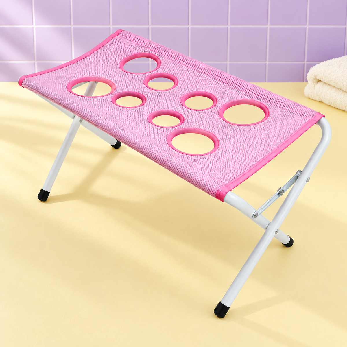 Styled visualization of the pink mesh grooming hammock and white folding stand against lavender tiles. Towel is a styling prop, not included.
